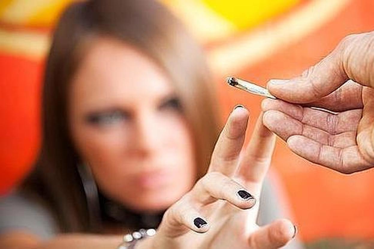 Un hombre ofrece un porro a una joven.