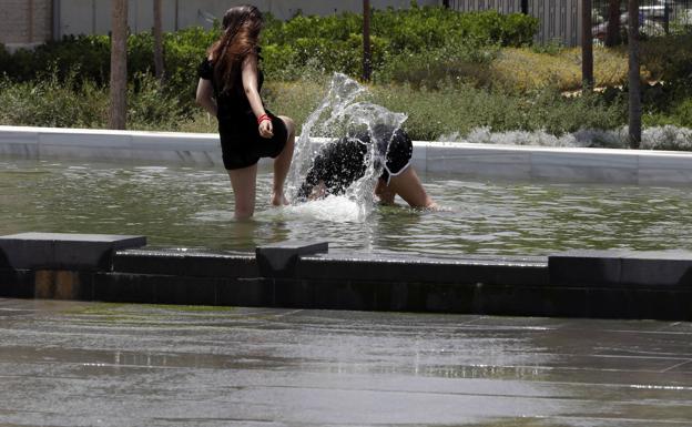 Dos jóvenes se refrescan este sábado en el Parque Central de Valencia.