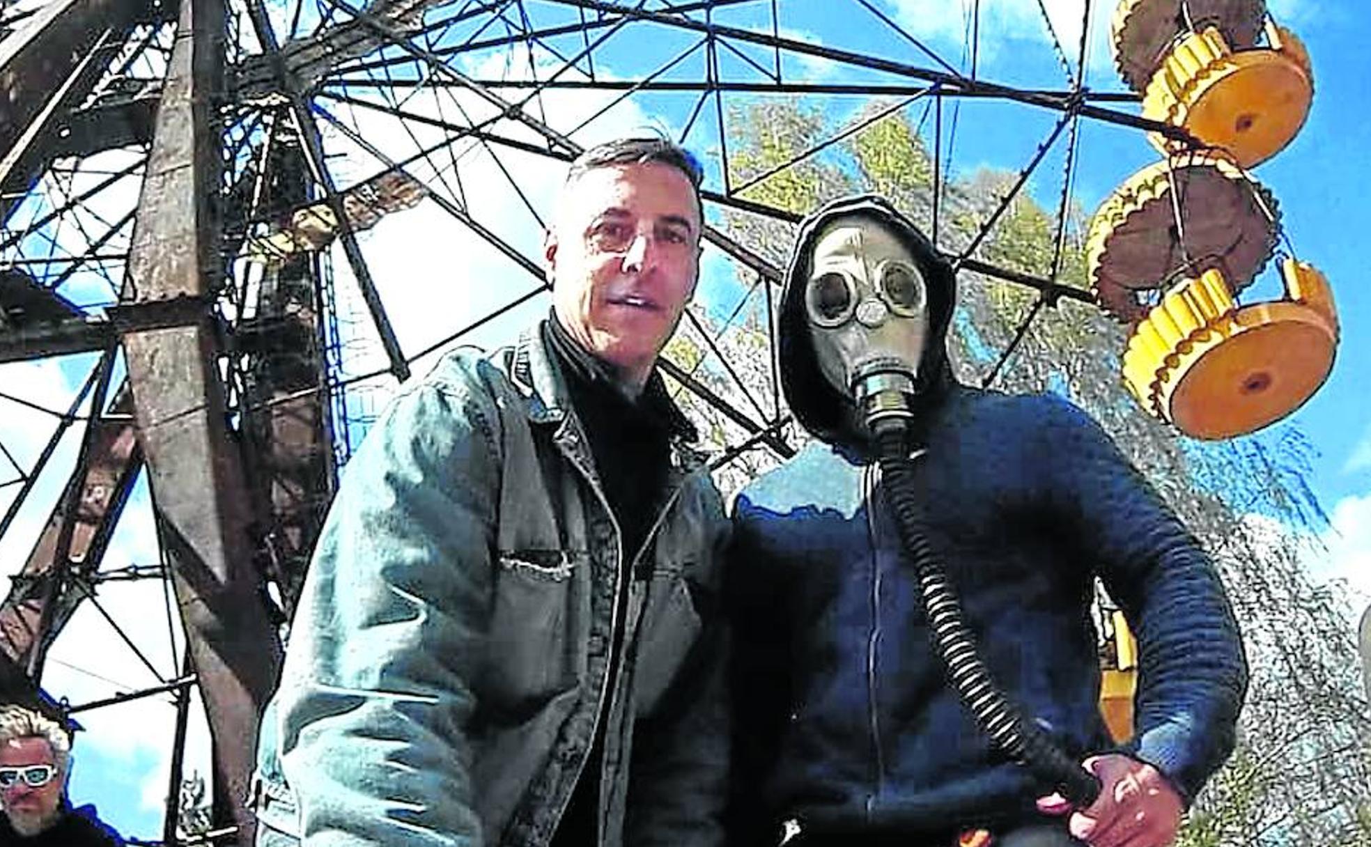 El viajero español Héctor Navarro posa junto otro turista con máscara frente a la noria de Luna Park, en Prípiat.