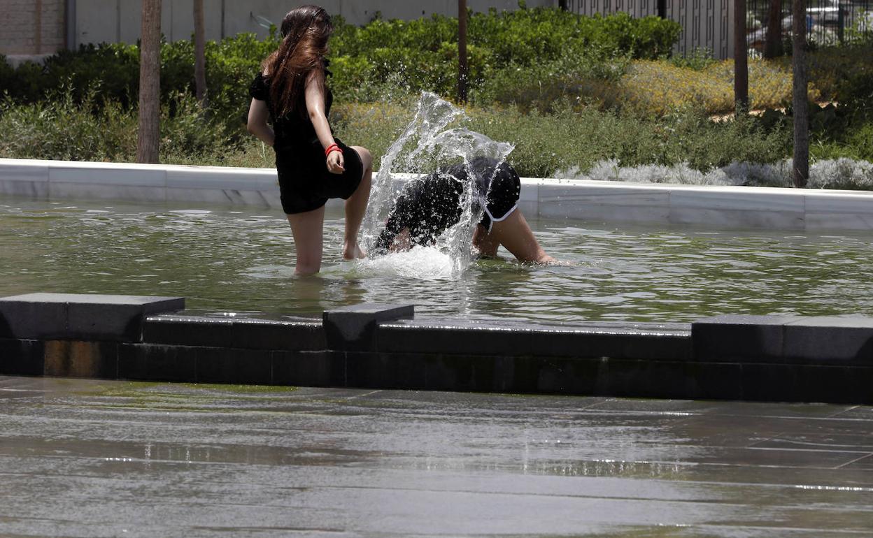 Dos jóvenes se refrescan en el parque Central de Valencia. 