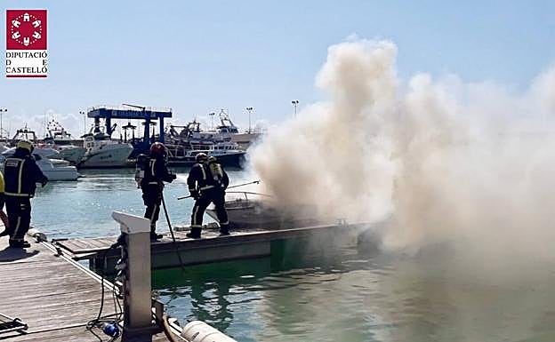 Imagen principal - Actuación de los bomberos extinguiendo el incendio de la embarcación. 