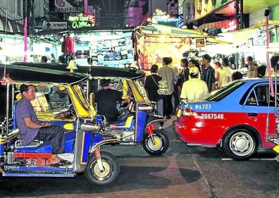 Imagen secundaria 1 - Chicas esperan a la entrada de un local. | Tuk tuks en el mercado nocturno. | Una turista recorre los puestos. 