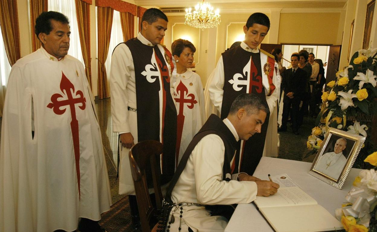 Miembros del movimiento Heraldos del Evangelio firman en un libro de honor ante una imagen de Juan Pablo II, su valedor. 