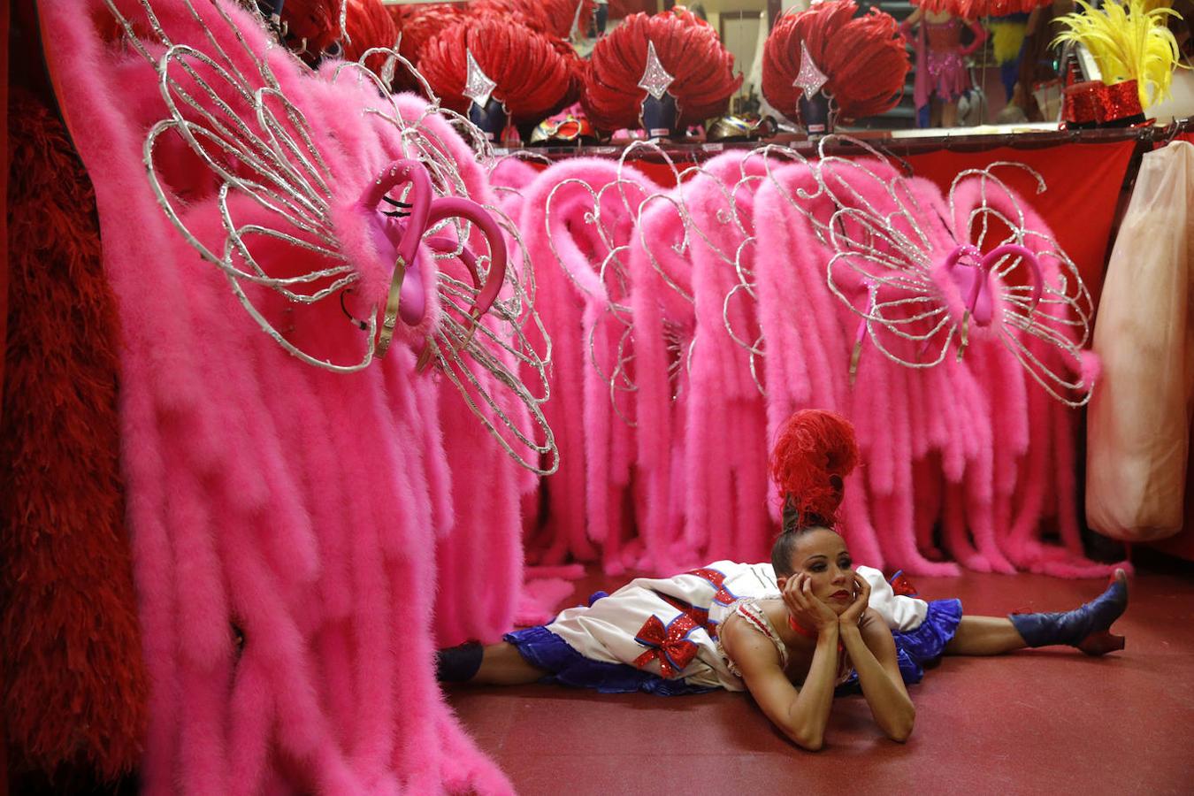 Cada vez que un número termina, se repite la misma escena: los bailarines se apresuran detrás del escenario. Allí, los trajes multicolores, muchos con incrustaciones de pedrería, han sido ordenados por un ejército de asistentes. Filas de plumas de color rosa cuelgan de los rieles.