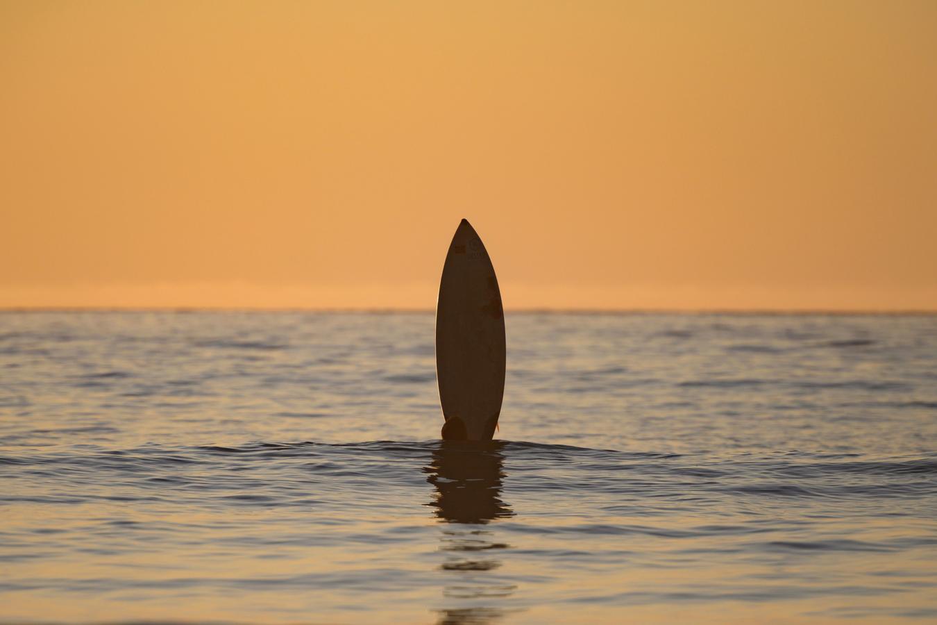 Un surfista juega con su tabla mientras espera una ola.