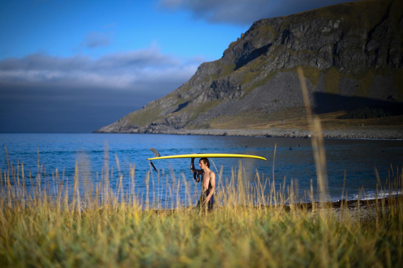 Un surfista lleva su tabla hacia el camión donde están los jueces del Open men Contest Lofoten Masters 2019.