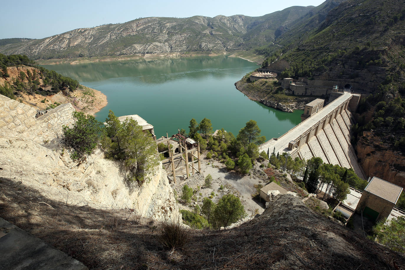 La cementera de Benagéber (Valencia) | La enorme construcción todavía se contempla desde lo lejos, como un colosal castillo de hormigón entre agua y maleza. Construida en la década de los cuarenta, fue gestionada por la misma empresa que se encargó del embalse, Portolés y Cía, que se convertiría en una de las principales compañías de obras públicas tras la Guerra Civil. La construcción del pantano de Contreras también corrió a cargo de esta firma, prueba de su estrecha colaboración laboral con el gobierno franquista. En aquella época, la mayoría de los habitantes de Benagéber eran los trabajadores de las obras del embalse y la cementera. Por ello, cuando en 1955 finalizaron los trabajos para la formación del pantano, la mayoría de la población emigró y el lugar quedó sumido en la escalofriante quietud que, a día de hoy, le sigue caracterizando. 