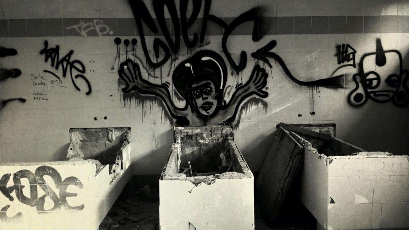 El psiquiátrico infantil abandonado de Cheste (Valencia) | Apenas existen datos concretos sobre su historia, pero sí se sabe que su nombre popular no se corresponde con la realidad de lo que fue. El centro 'La Humanitat' jamás fue un psiquiátrico, sino un centro asistencial para pacientes con distintos grados de deficiencias físicas y psíquicas. Las leyendas que circulan sobre él aseguran que residían aquí niños y enfermos mentales potencialmente peligrosos. La residencia pasó a formar parte en 1986 del Consorcio Valenciano de Servicios Sociales (Convaser) y con el tiempo sus instalaciones dejaron de servir para el modelo asistencial que se pretendía cubrir. El lugar quedó abandonado, objeto de bulos urbanos y objetivo de los adeptos a lo paranormal. La más conocida es la 'leyenda del pasillo quemado' según la cual una enferma o interno prendió fuego al pasillo del ala derecha, ocasionando un incendió en el que -por supuesto- murieron varias personas (según se dice, niños). El lugar, desde luego, da para mucho. Entre muebles, grafitis y pintadas, el pasillo sigue quemado y aún conserva, aunque destrozadas, las bañeras y los aseos que empleaban los residentes. 