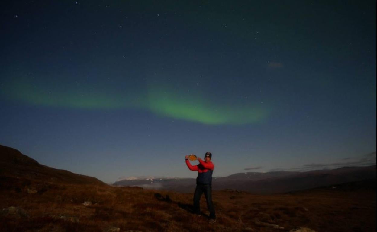 Federico Arrizabalaga, sujetando una paella con las auroras boreales de fondo. 