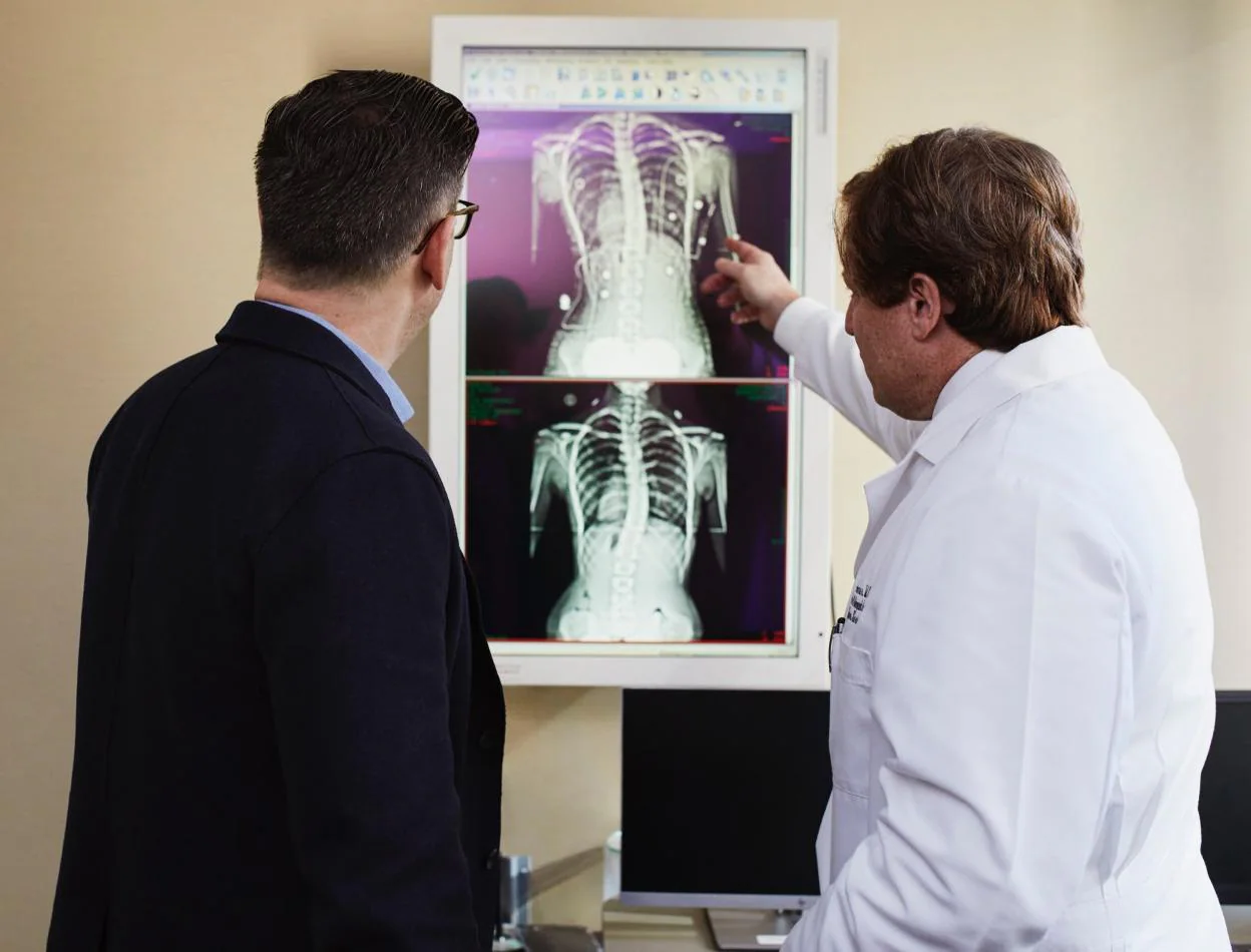 Un sanitario enseña una radiografía a un paciente. 