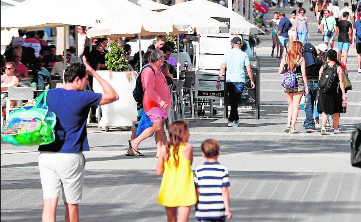 Viandantes paseando por el paseo de la Malvarrosa.