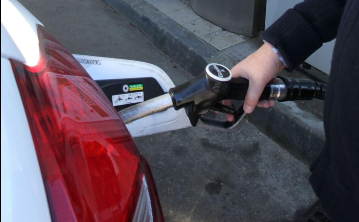 Un hombre, repostando un coche en una gasolinera.