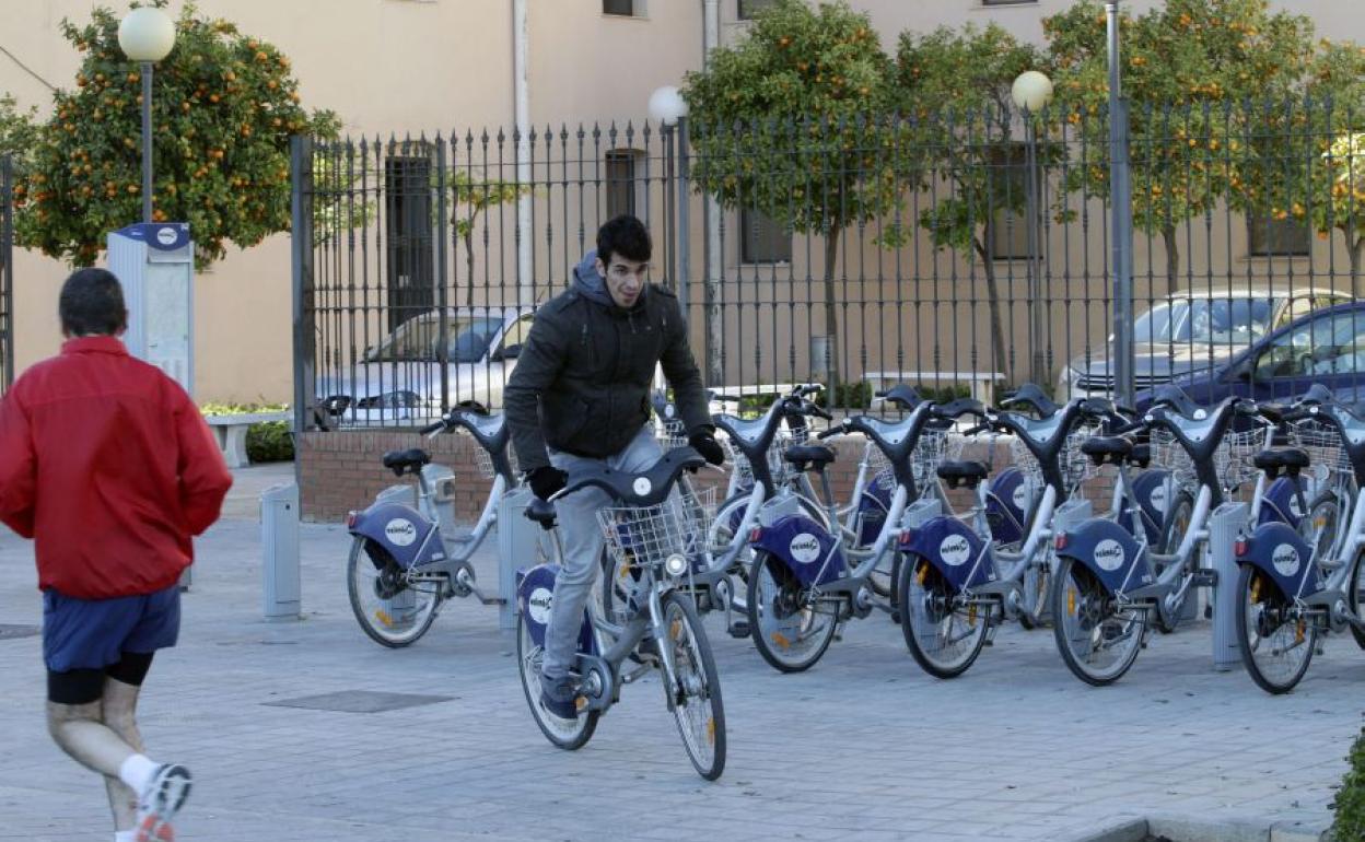 Un joven circula por delante de una estación de Valenbisi.