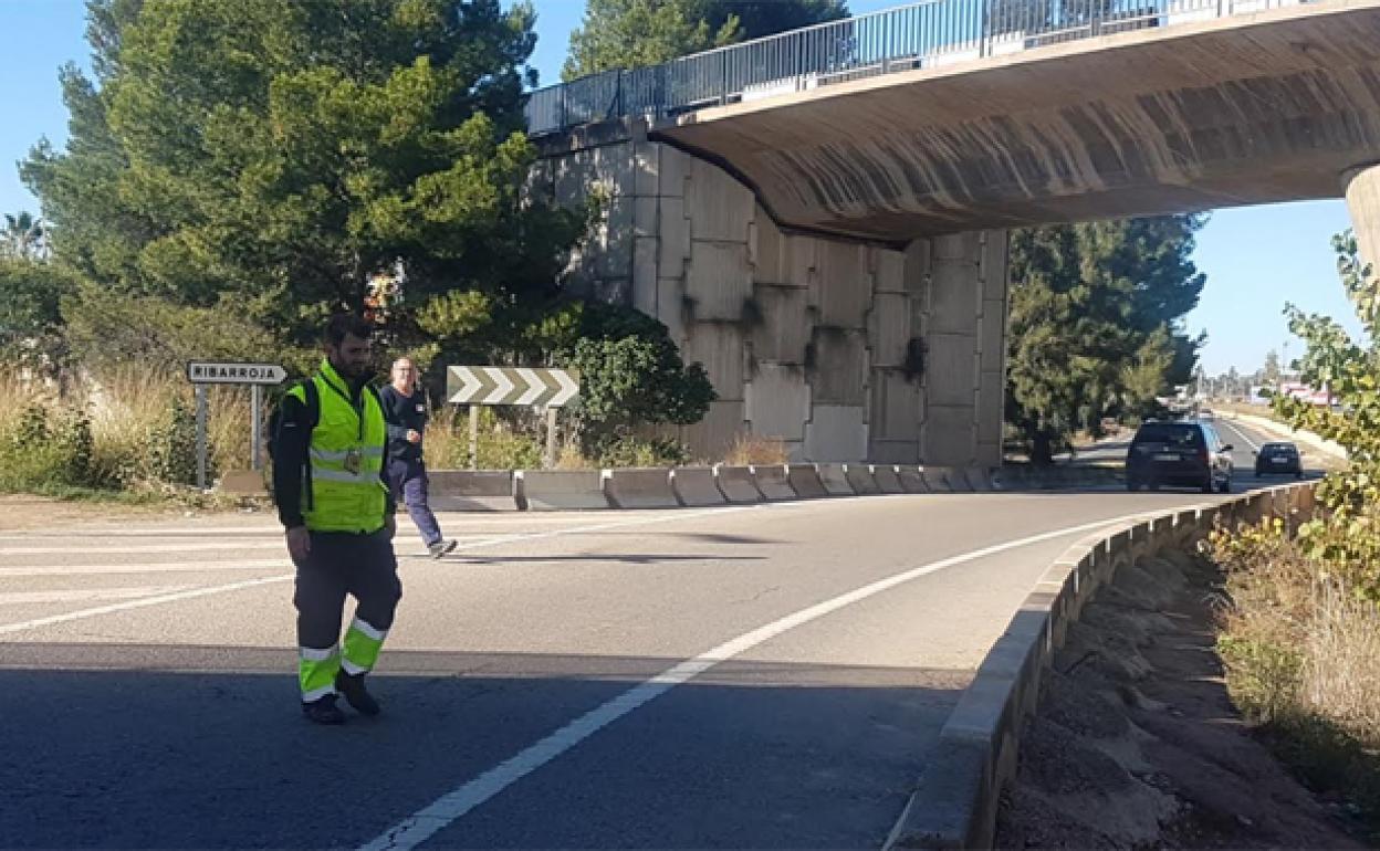 Dos peatones cruzan por el lugar donde murió atropellada una persona el sábado, justo después de que pasen dos coches.