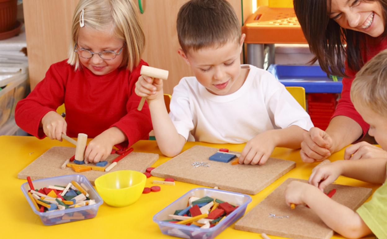 Tres niños y un adulto, con un juego educativo.