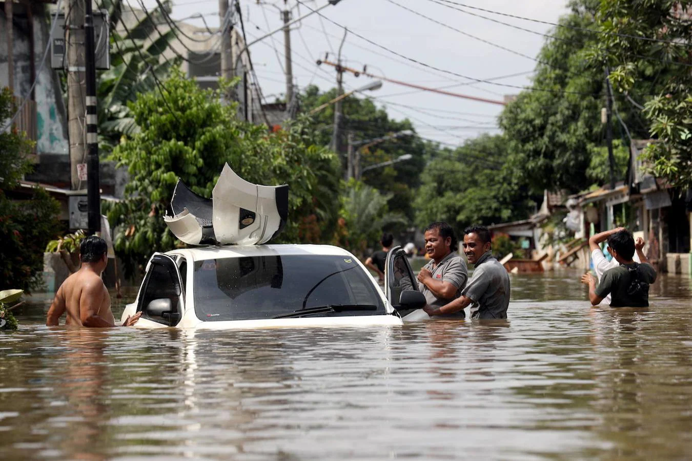 Un grupo de hombres tratan de remolcar un coche arrastrado por las inundaciones de Yakarta, Indonesia.