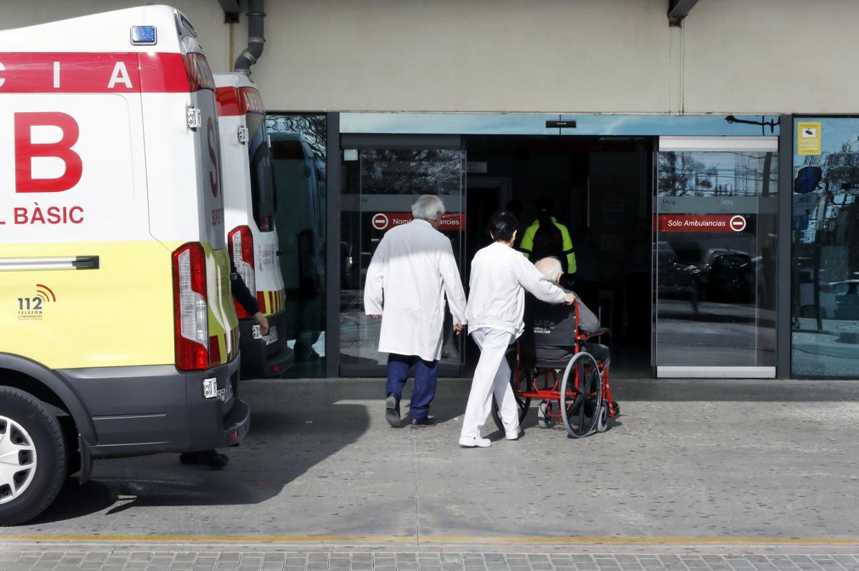 Personal sanitario acompaña a un paciente hacia una de las entradas del hospital La Fe, este lunes. 