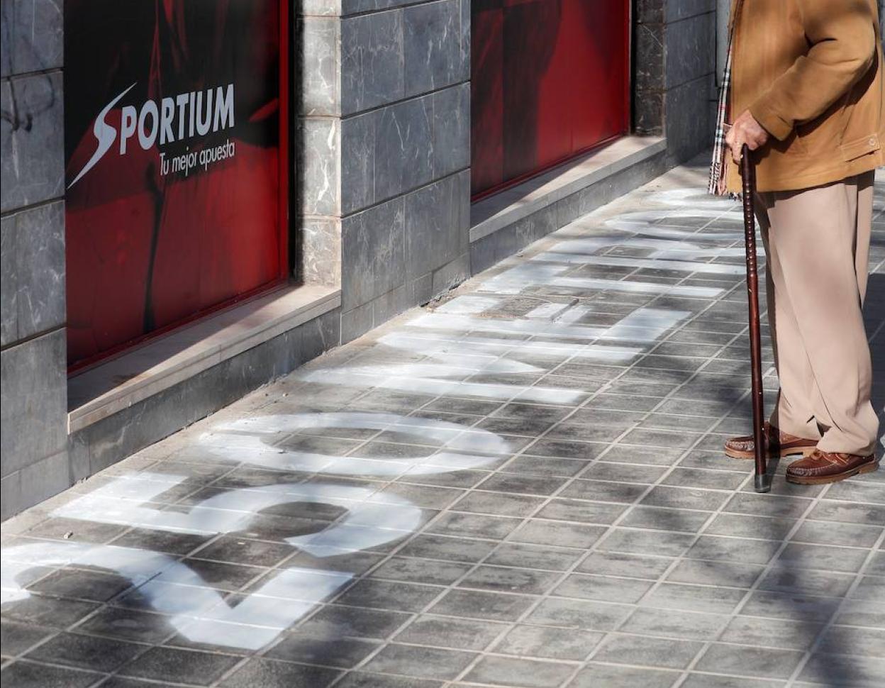 Un señor contempla la pintada de «250 metros» ante una casa de apuestas de Valencia.