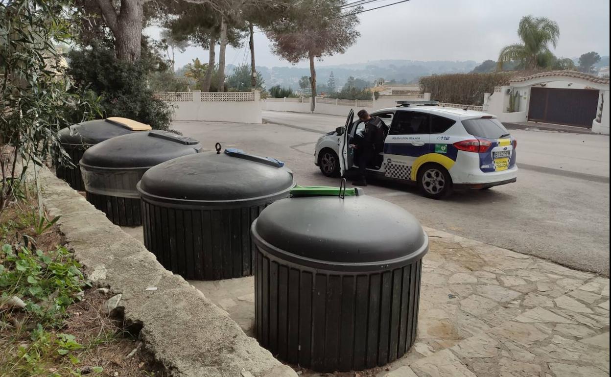 Uno de los agentes de la Policía Local junto a los contenedores donde hallaron el cadáver de la mujer.