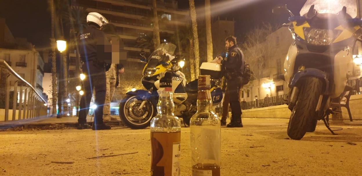 Varios agentes de la Policía Local de Alicante requisan dos botellas con contenido alcohólico a un joven disfrazo durante la noche de Carnaval. LP