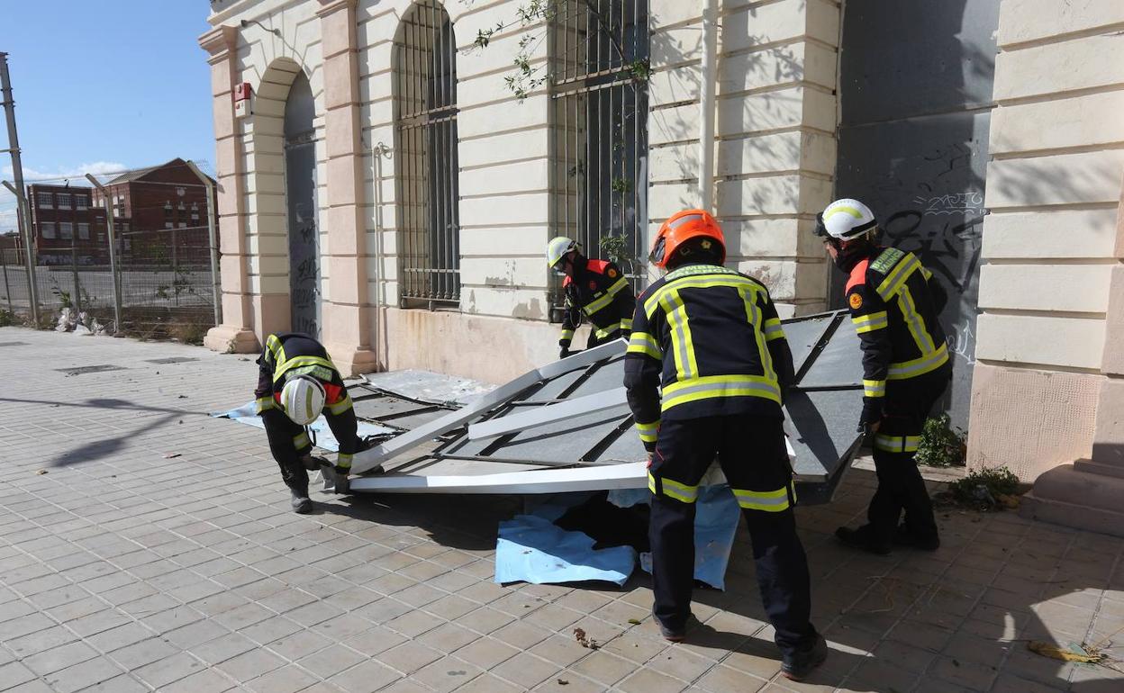 Los bomberos de valencia retiran un cartel tirado por el viento. 