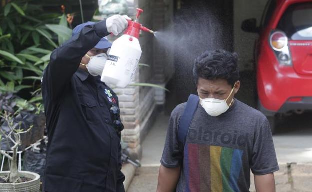 Un hombre rocía con un espray desinfectante a los vecinos de una localidad de Depok, en Indonesia.