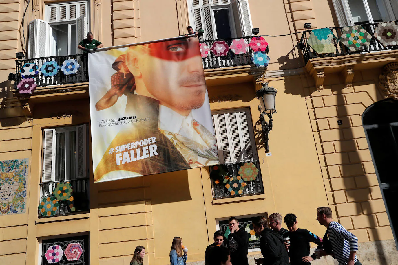 Operarios desmontan un cartel oficial de las Fallas 2020 en una de las calles de Valencia.