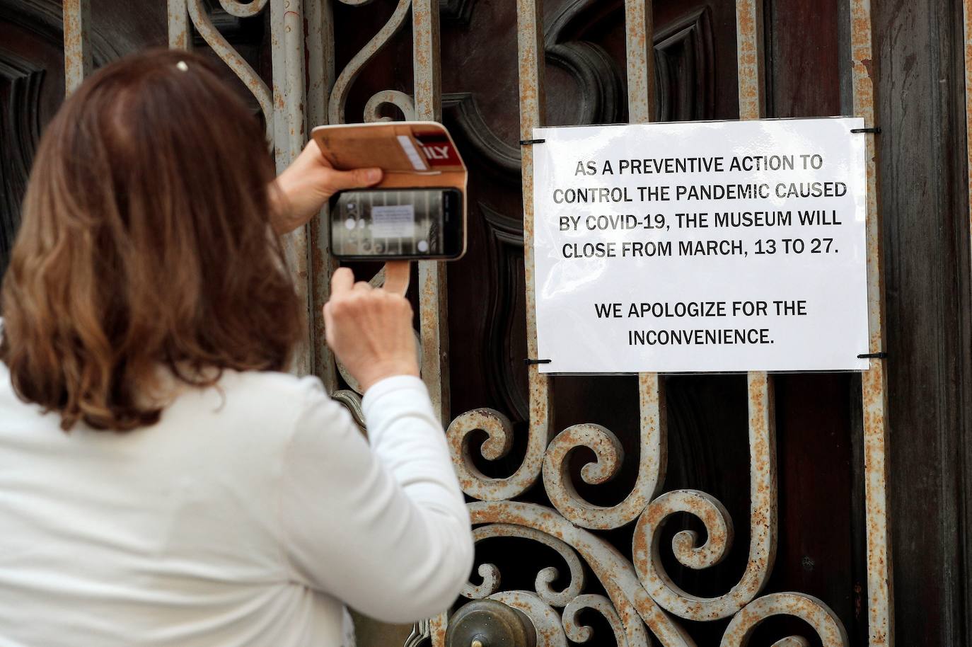 Una mujer fotografía un cartel en inglés que anuncia el cierre de las instalaciones del Museo Nacional de Cerámica de Valencia. 