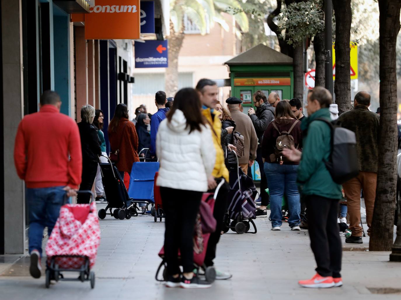 Sigue la avalancha de compras por el miedo a la pandemia del coronavirus. Los supermercados valencianos llevan ya varios días notando la falta puntual de productos como el agua embotellada, las pasta o el papel higiénico. Este sábado, multitud de tiendas y comercios de alimentación de Valencia han amanecido con largas colas de clientes esperando a la apertura de puertas. En la imagen, compradores esperan frente a las puertas de un supermercado Consum en el centro de Valencia.