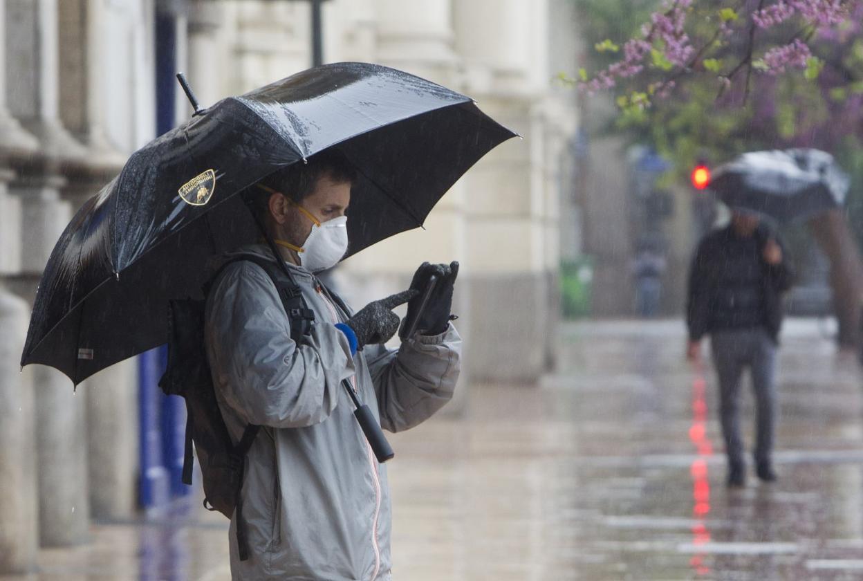 Un hombre se protege de la lluvia con un paraguas ayer en Valencia. damián torres