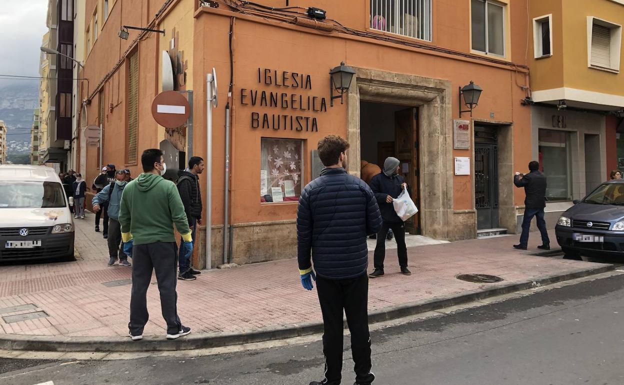 Los usuarios del comedor de Extiende tu mano, ayer, haciendo cola y recogiendo sus alimentos. 