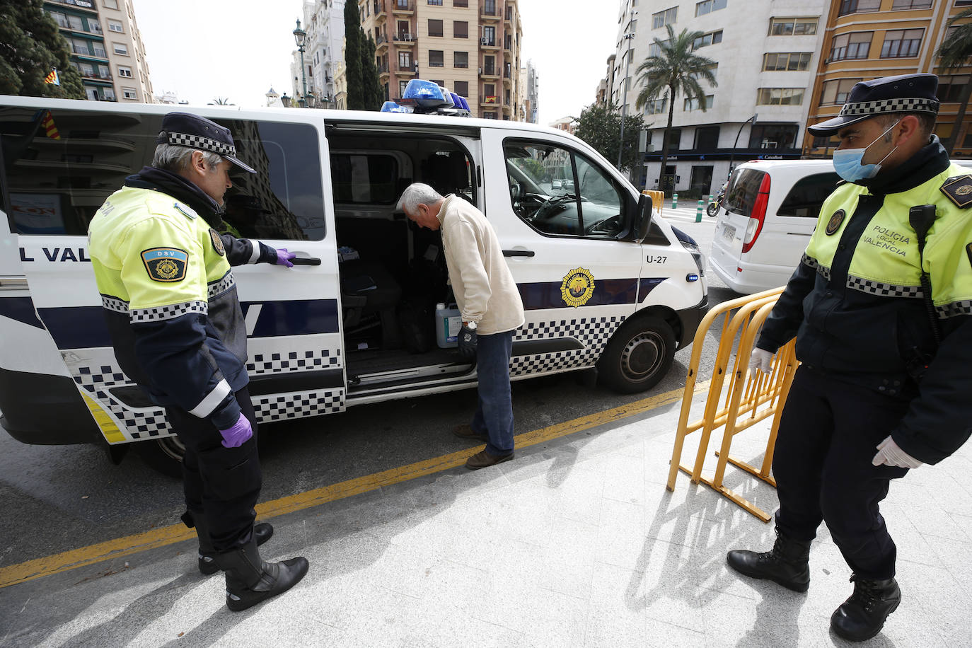 Un ciudadano proporciona de forma altruista solución antiseptica a los agentes de Policia Local de Valencia que controla los accesos de trafico en la calle Ruzafa. 