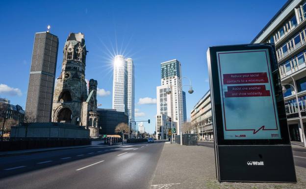 La iglesia conmemorativa Kaiser-Wilhelm, el edificio 'Upper West', el edificio 'ÄôZoofenster' en Berlín se ven frente a una pantalla en la que se lee «Reduce tus contactos sociales al mínimo. Ayúdense unos a otros y demuestren solidaridad''