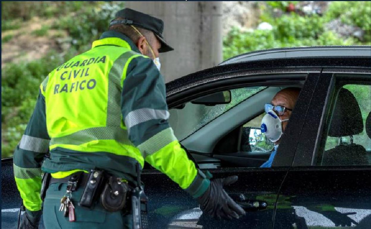 Un agente de la Guardia Civil de Tráfico de la Comandancia de Sevilla conversa con un conductor con mascarilla durante un control. 