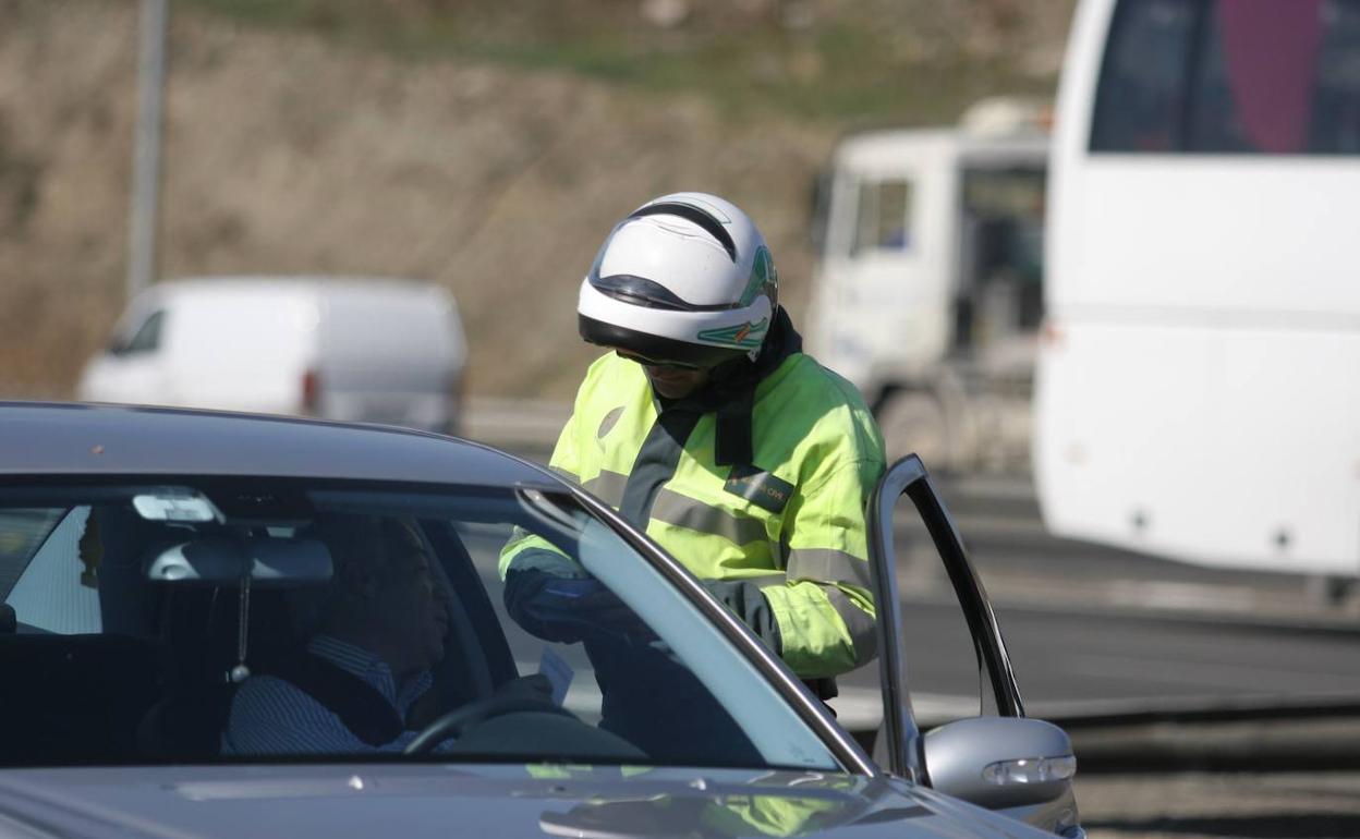 Un agente de Tráfico multa a un conductor en una carretera.