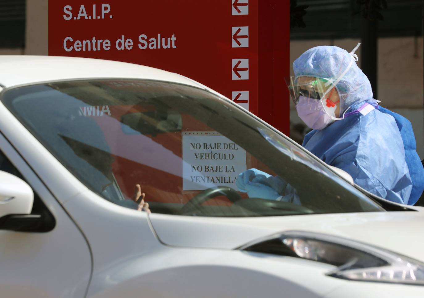 Miembros del hospital de la Malvarrosa, en Valencia, realizan tomas de muestra rápidas al personal sanitario sin que los conductores bajen del vehículo. 