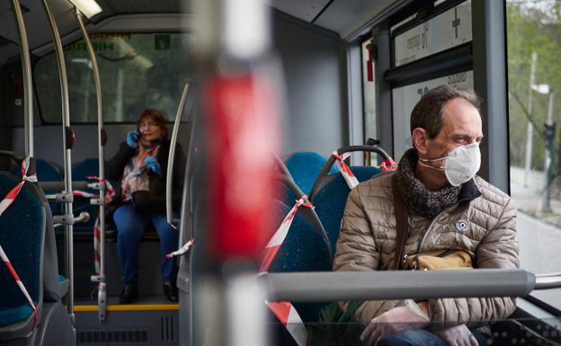 Un hombre viaja con mascarilla en un autobús urbano.