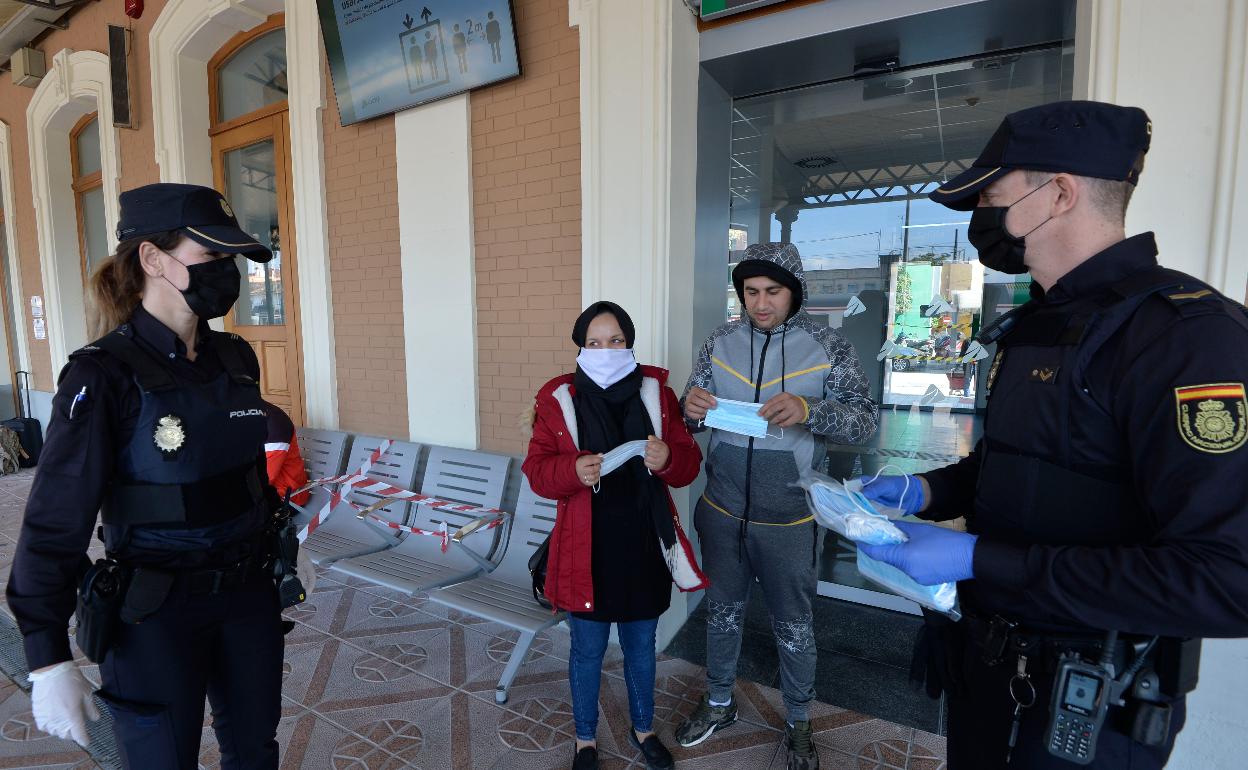 Dos policías reparten mascarillas en una estación de tren. 