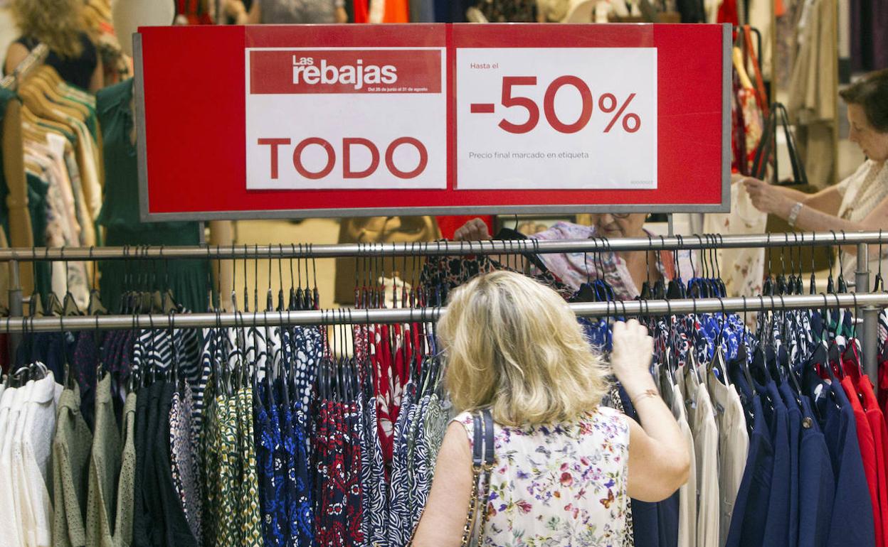Una mujer observa la ropa rebajada de una gran superficie. 