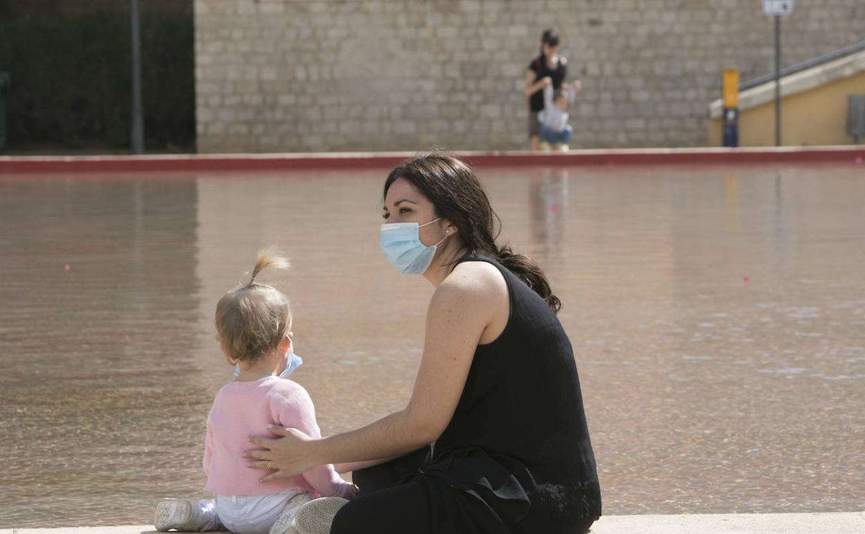 Una niña y su madre, ambas con mascarillas. 