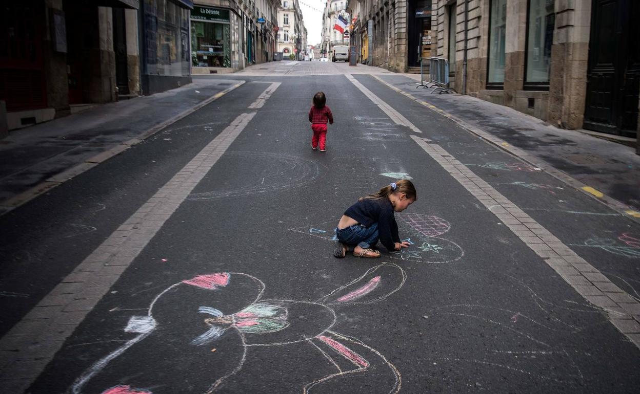 Una niña dibuja con tiza sobre el asfalto de una calle desierta de Nantes.