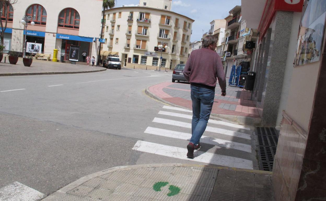 Una persona sigue la dirección que marcan las huellas pintadas en las aceras de Teulada. 