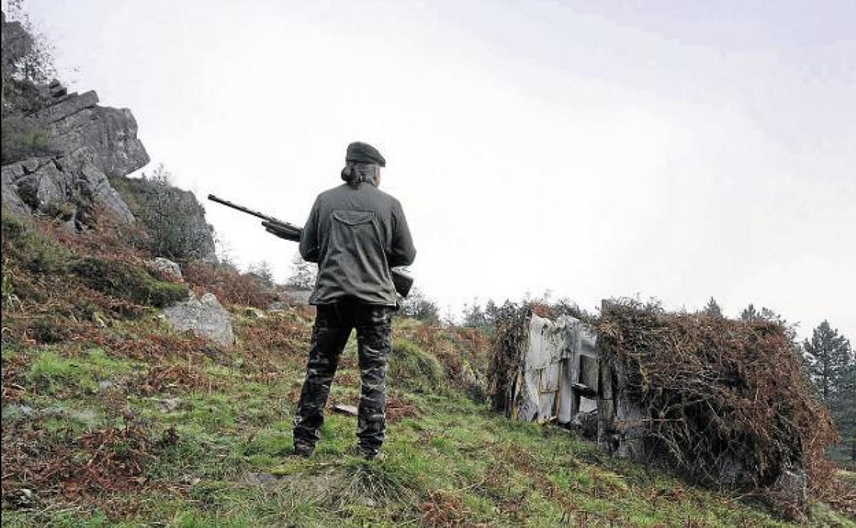 Un cazador otea un paraje mientras sostiene su escopeta.