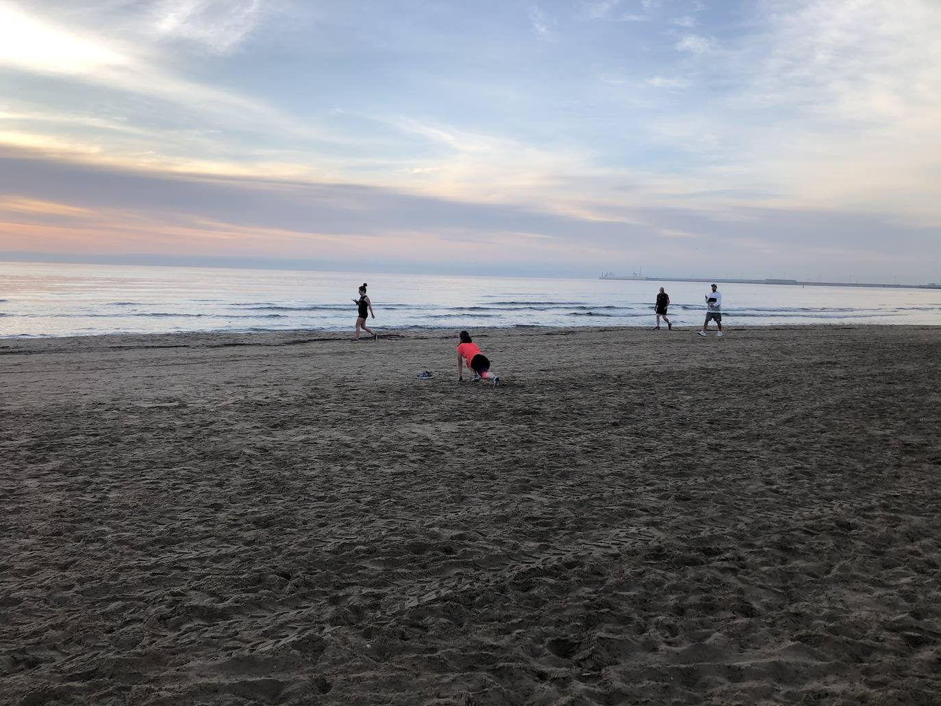 Nadadores, corredores, surfistas y personas practicando yoga se han dejado ver este jueves en las playas de Valencia desde que se ha asomado el sol, aprovechando las horas permitidas para practicar deporte en la ciudad. 