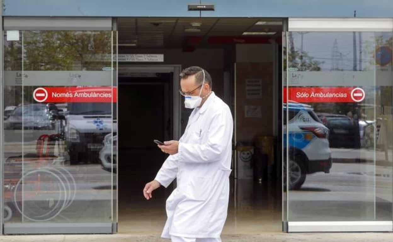 Un m édico con mascarilla pasa junto a una de las puertas de La Fe de Valencia.