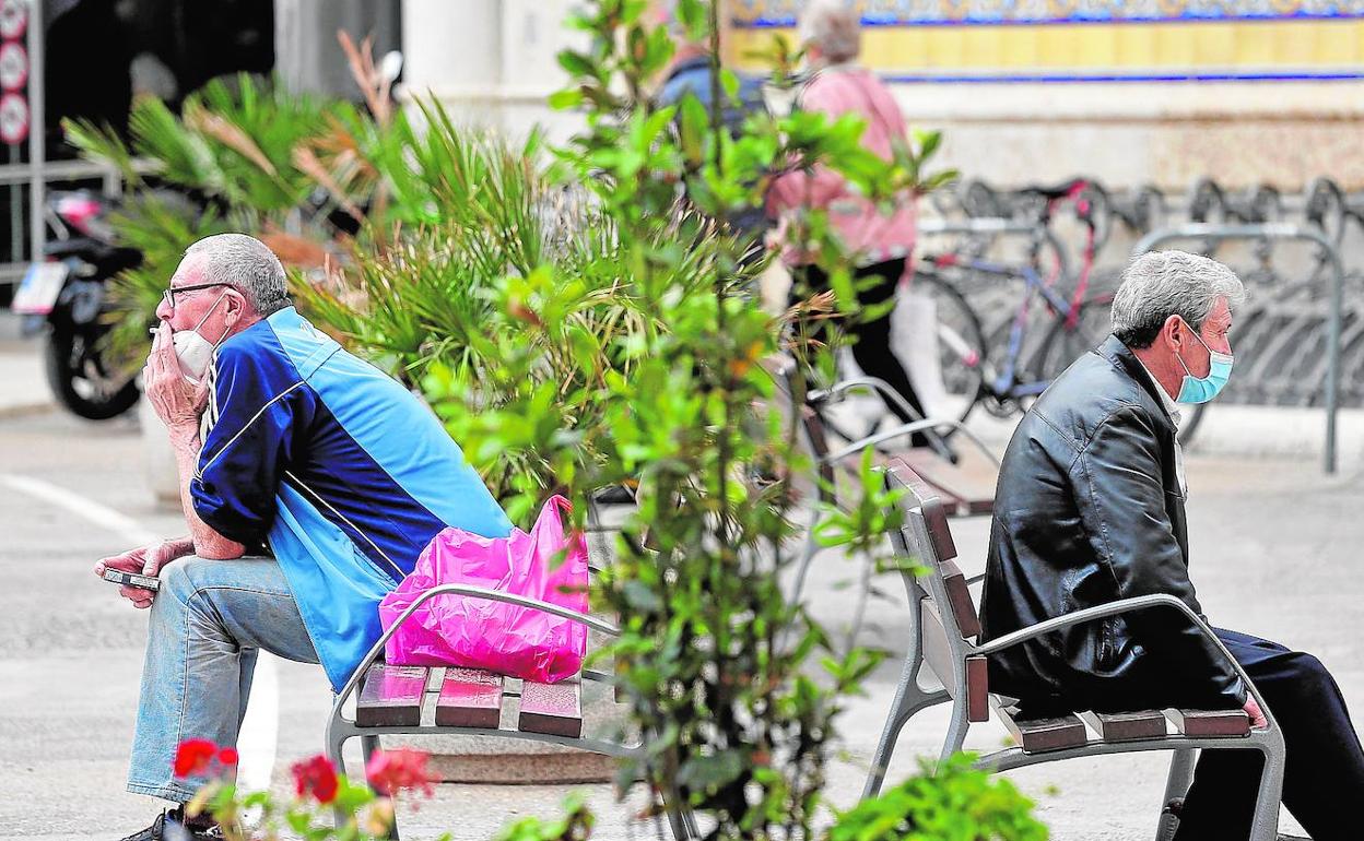 Dos hombres descansan en sendos bancos, ayer en el centro de Valencia.