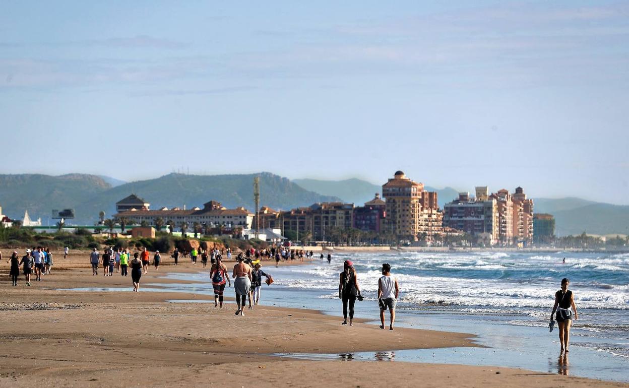 Ciudadanos pasean por la playa de Alboraya, este domingo.