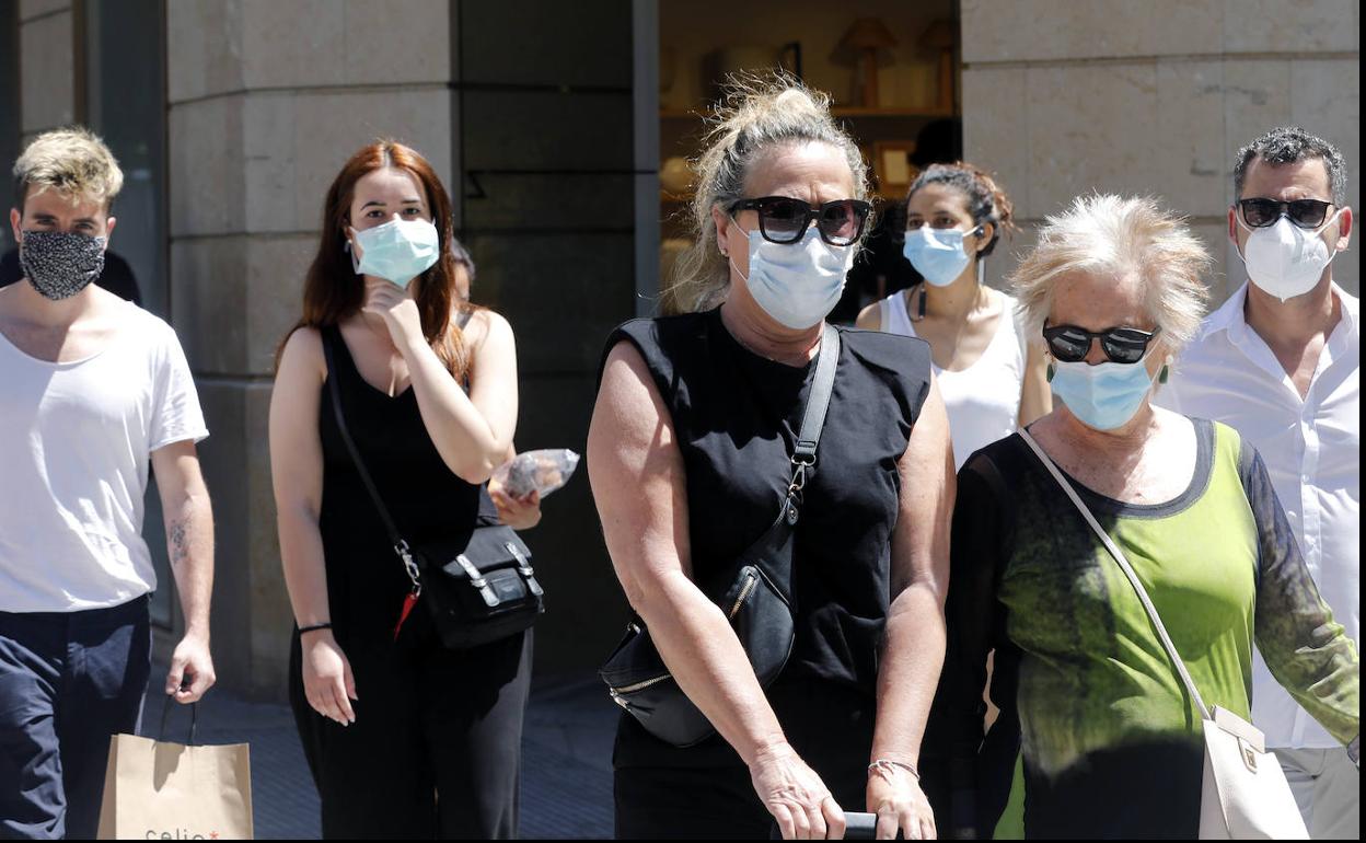 Varias personas circulan por Valencia con mascarillas. 