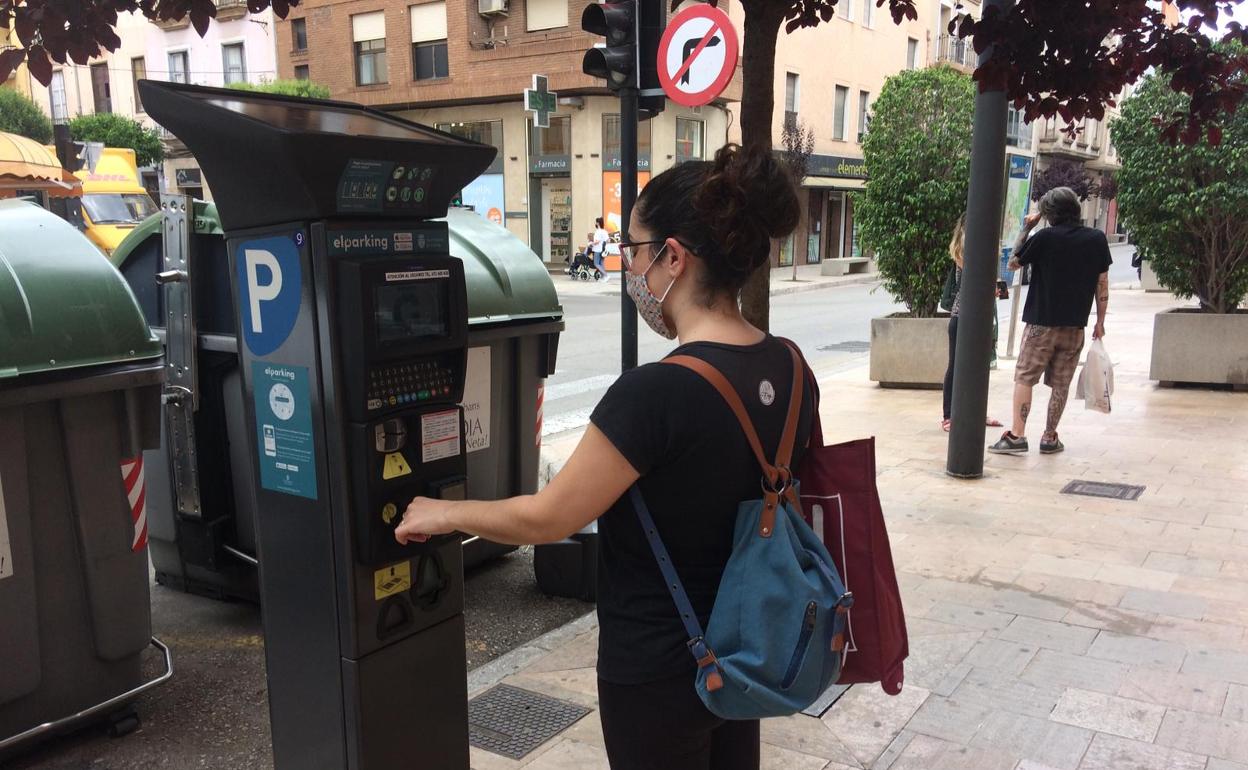 Una joven saca un tíquet en un expendedor de Gandia.