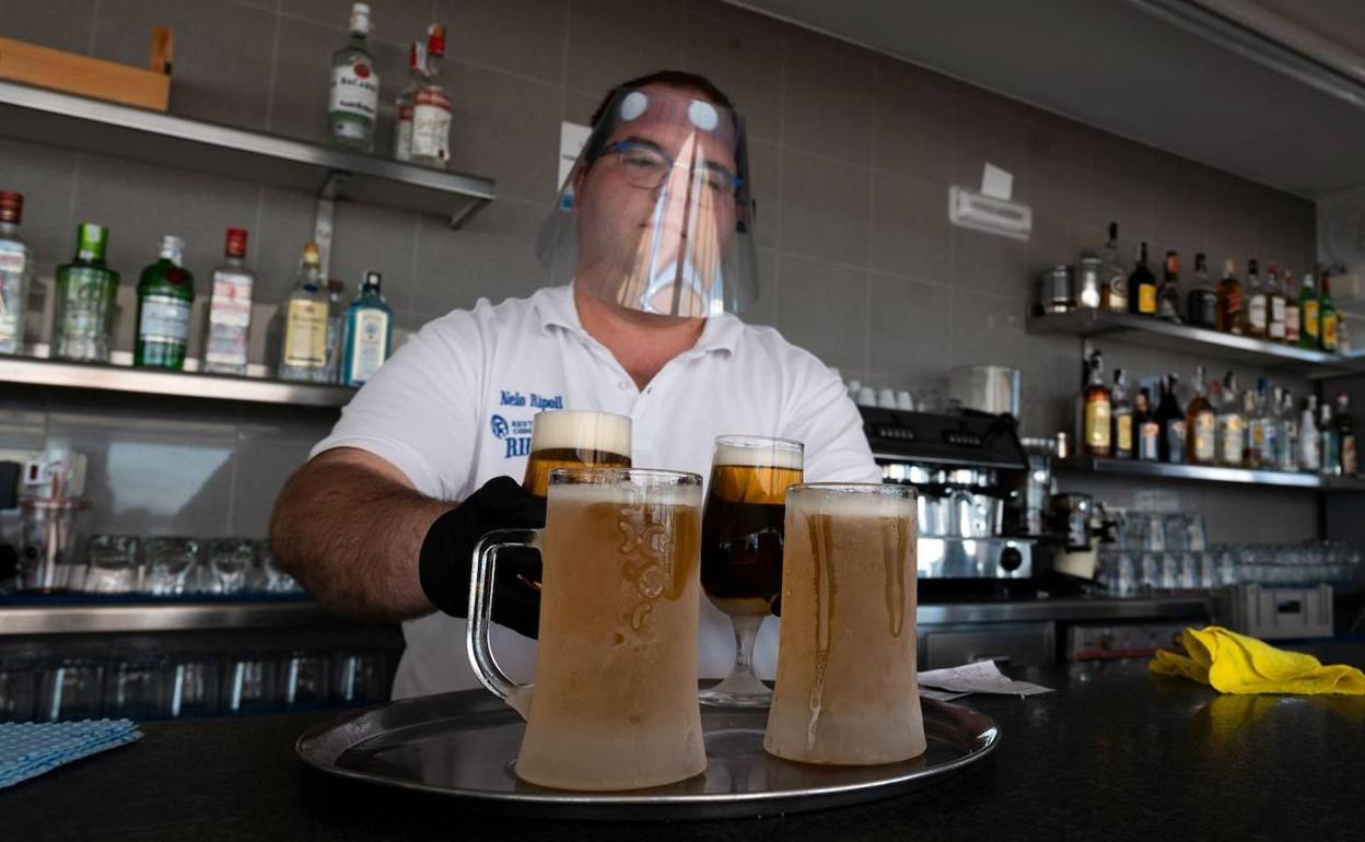 Un camarero lleva una pantalla protectora en un bar de Valencia.